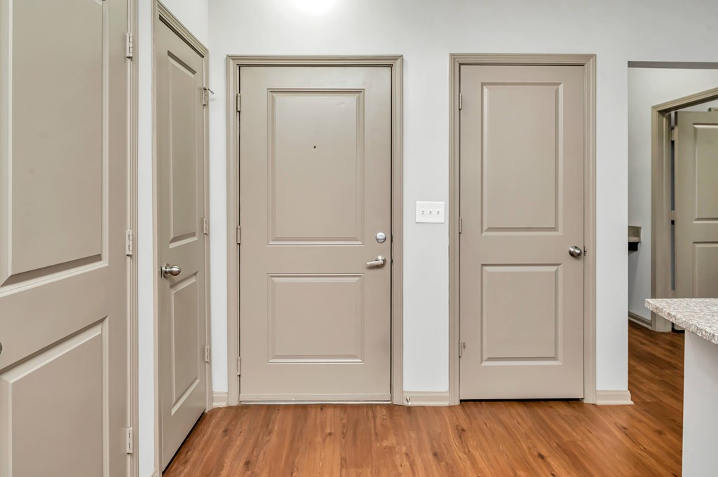 A hallway with three doors and a white counter.